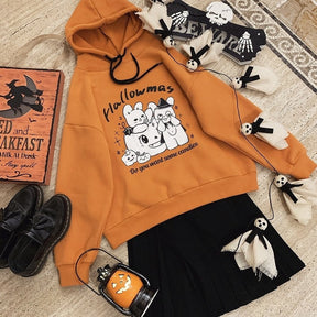 Orange rabbit-and-pumpkin hoodie arranged diagonally beside a black skirt, shoes, ghost decorations and a pumpkin lantern.