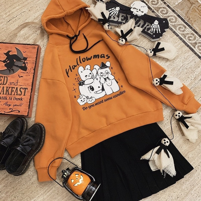 Orange rabbit-and-pumpkin hoodie arranged diagonally beside a black skirt, shoes, ghost decorations and a pumpkin lantern.