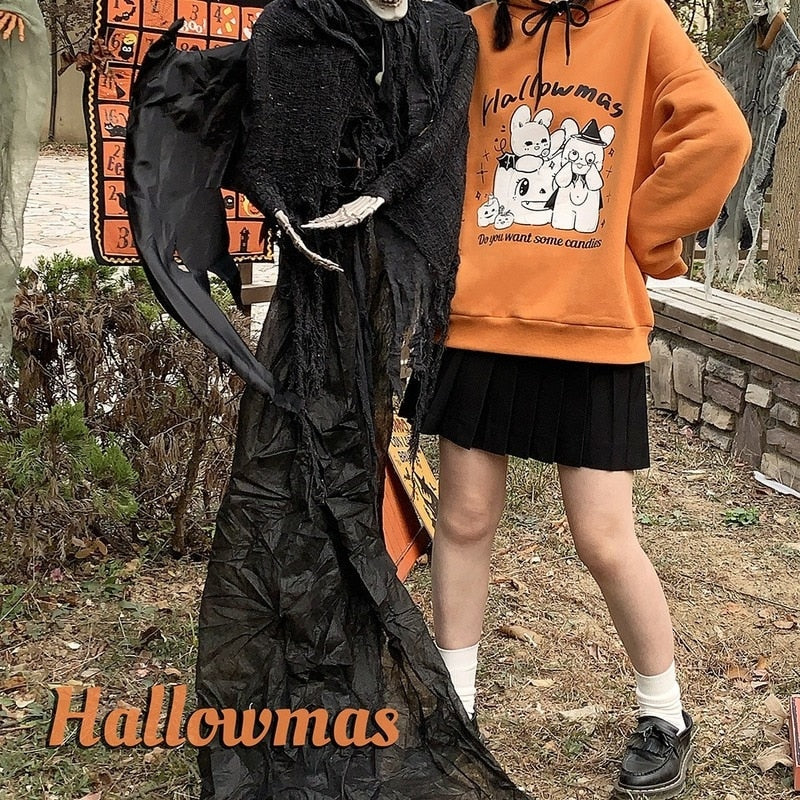 Orange Hallowmas hoodie styled with a black skirt beside a dark Halloween figure, with overlaid lettering at the bottom of the image.