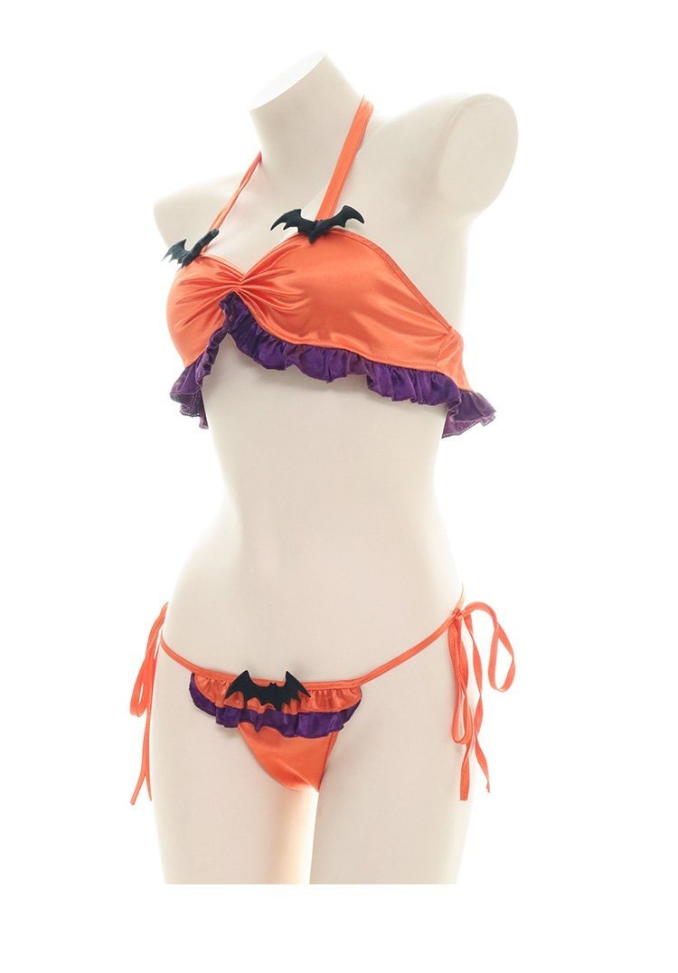 Portrait view of the orange bat lingerie set on an angled mannequin, with purple ruffles beneath the gathered top and along the front of the tie-side bottoms.