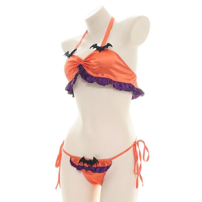 Three-quarter front view of the orange and purple Halloween lingerie set on a mannequin, showing the gathered halter top, black bats and tied sides of the matching bottoms.