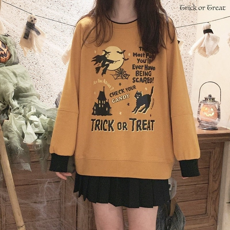 Front outfit view of the orange Halloween crewneck sweatshirt with a black skirt and dark underlayer extending beyond the cuffs.