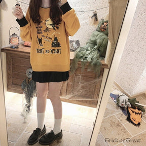 Orange Halloween crewneck sweatshirt in a full-length mirror outfit, with hands raised near the shoulders and a short black skirt below the hem.