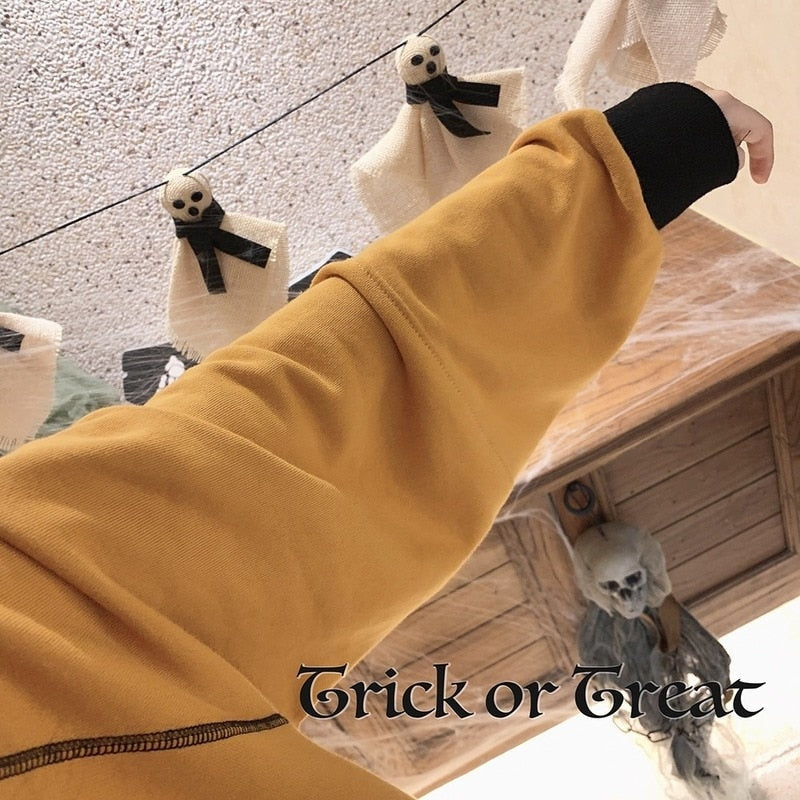 Detail of the orange Trick or Treat sweatshirt sleeve stretched forward, showing the seam and ribbed cuff above a black underlayer.