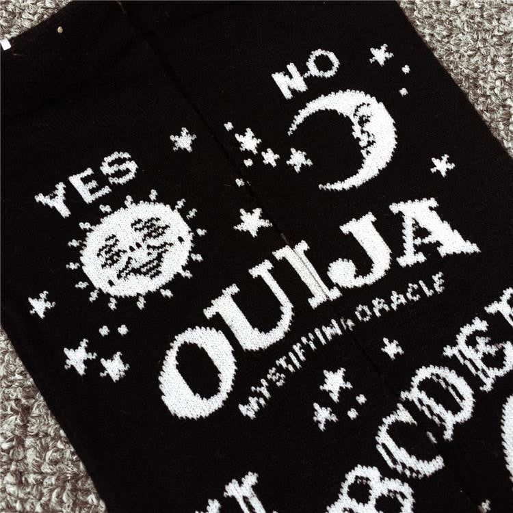 Close view of white Ouija lettering on black socks, with a sun marked Yes, a crescent marked No and scattered stars.