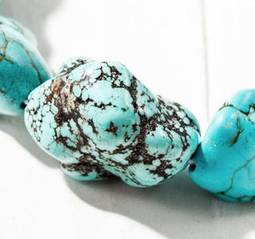 Close view of the oval turquoise-coloured stones, showing their uneven rounded shapes and dark surface veining.