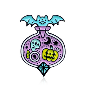 Lavender Halloween potion-bottle enamel pin on white, topped with a turquoise bat. A ghost, yellow-green pumpkin, eyeball, candy corn, crescent moon and stars fill the bottle above a turquoise diamond-shaped accent.