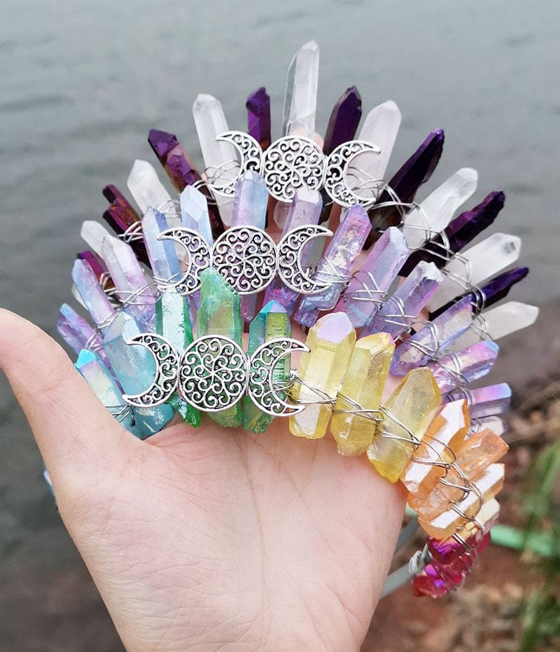 A group of pale triple moon crowns with purple, clear and pastel rainbow crystal points around silver-tone lunar emblems.