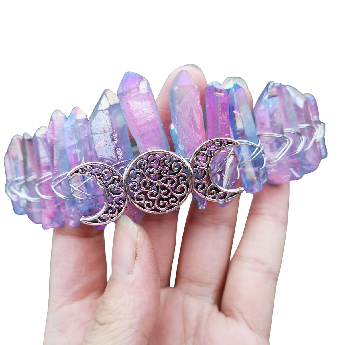 Close view of a pastel rainbow crystal crown on white, with a silver-tone triple moon emblem beneath pale pink, blue and yellow points.