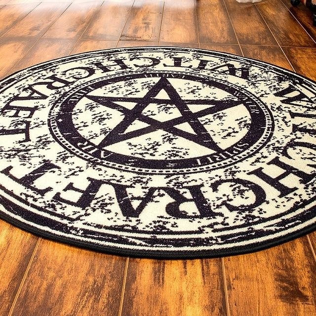Low angled view of the round pentagram rug, showing its printed surface and bound outer edge.