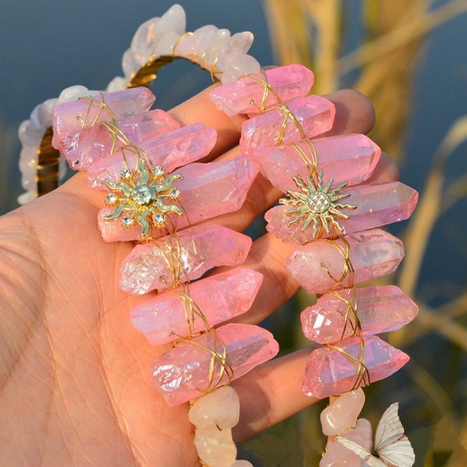 Two pink crystal tiaras held together, comparing their gold-tone sun face and sharper sunburst designs.