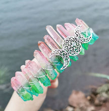 Angled view of a pink green crystal point crown with a silver-tone triple moon emblem and wire-wrapped band.