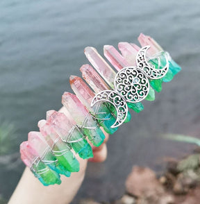 Angled view of a pink green crystal point crown with a silver-tone triple moon emblem and wire-wrapped band.