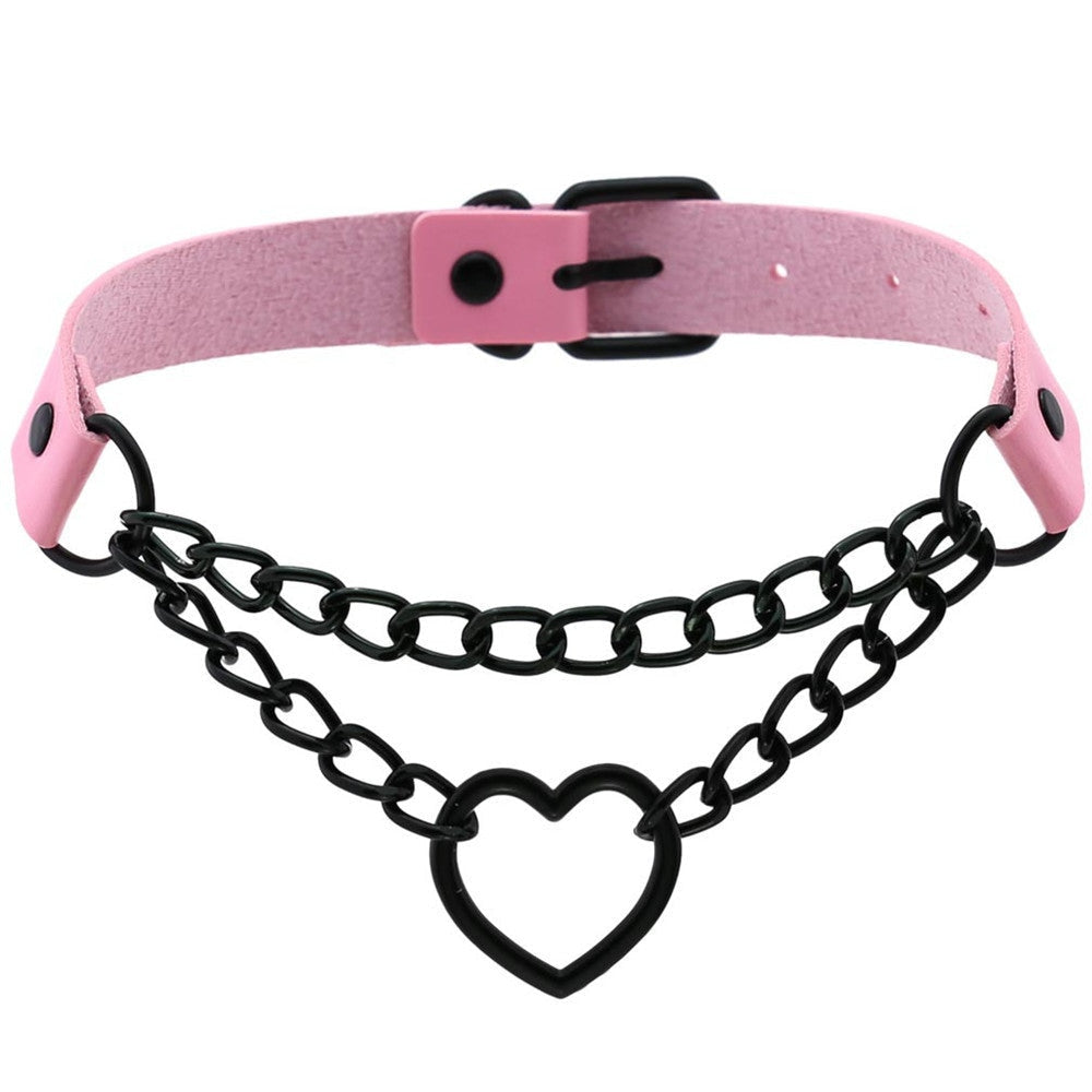 Pink faux leather choker with black double chains and an open black heart at the center, shown with the back buckle closed.