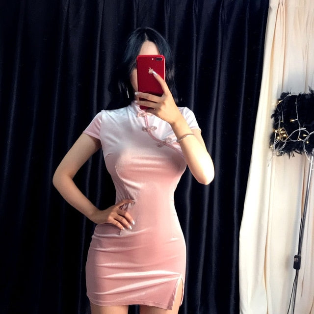 Pink velvet mandarin-collar mini dress worn in a mirror photo, with one hand on the waist and contrasting neckline trim.