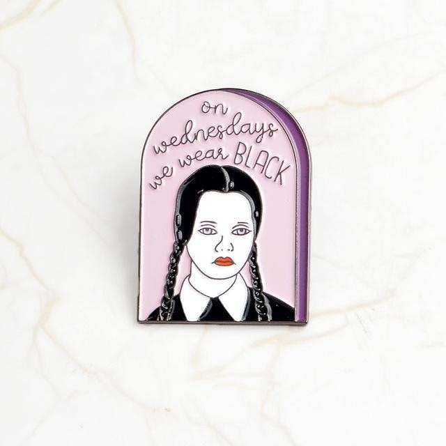 Pink arched enamel pin with a braided portrait in black and the words On Wednesdays We Wear Black.