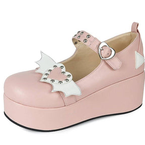Pink platform Mary Jane shoe with white bat wings around a studded pink heart, shown with a heart-shaped buckle and rounded toe.