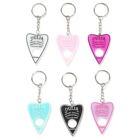 Six planchette keychains arranged in two rows on white, showing white, pale pink, bright pink, aqua, black and pale lavender designs with contrasting lettering.
