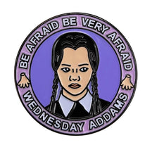 Round purple enamel pin with a black-braided portrait, white collar and Be Afraid, Be Very Afraid lettering around the top.