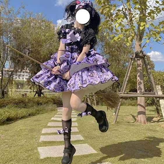 Full outdoor view of the purple tiered Halloween dress with a black underblouse and dark socks, with one leg lifted to show the platform shoe.