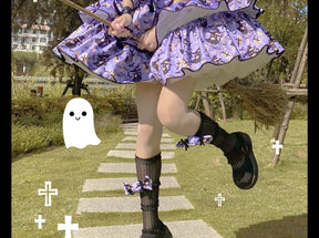 Detail of the purple Halloween dress skirt and hem outdoors, with black-edged printed tiers above dark socks and shoes.