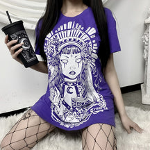 In Goth We Trust graphic T-shirt in Purple, worn in a seated outfit with the white illustration visible.