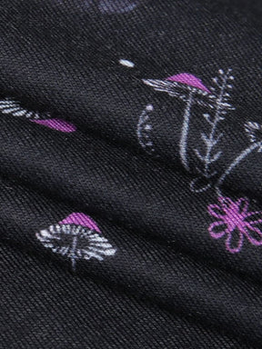 Macro view of the black dress fabric, showing its fine texture beneath purple mushroom caps, flowers and pale botanical outlines.
