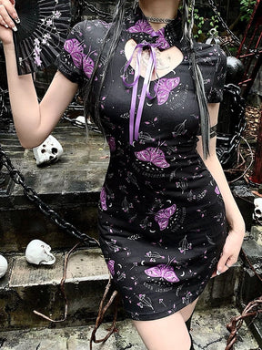 Purple moth mini dress styled with a black folding fan, showing the high ribbon-tied collar, keyhole neckline and fitted short skirt.