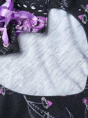 Rounded keyhole cutout of the black purple-moth dress shown flat on a pale surface, with the ribbon-laced collar visible at the top.