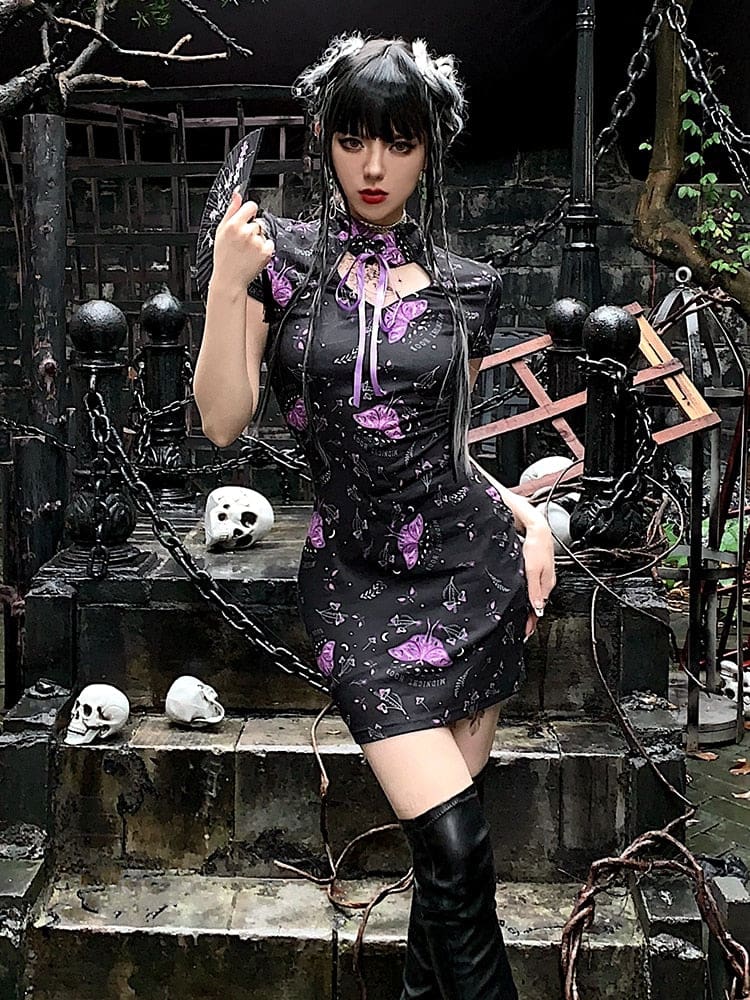 Full outfit view of the black purple-moth dress and tall boots on outdoor stone steps, with chains and skull decorations in the background.