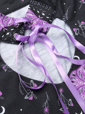 Close detail of the purple ribbon bow and eyelets at the front of the black moth dress collar, with the rounded keyhole opening below.