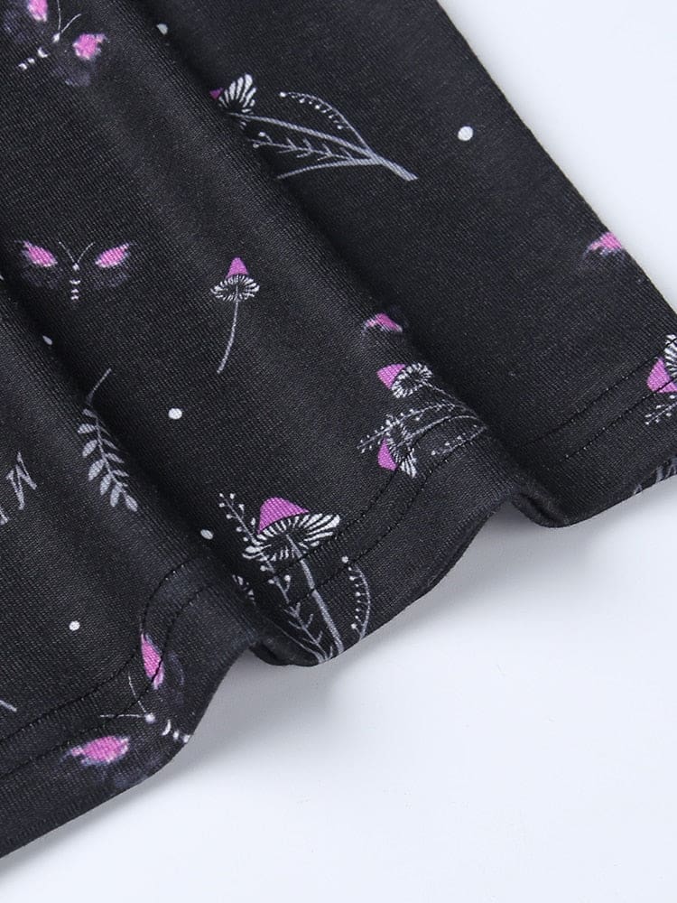 Short sleeve of the black moth dress shown flat, with a stitched cuff edge and small purple mushrooms and botanical motifs.