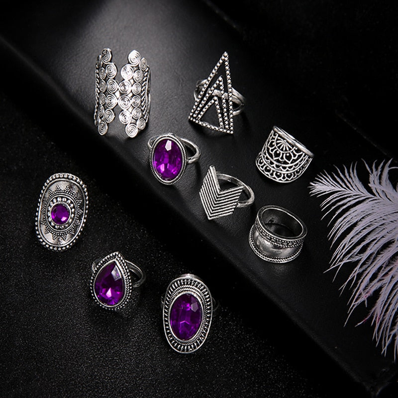 Nine-piece silver-tone ring set with purple jewel-like accents shown with the geometric bands and purple accents on black.