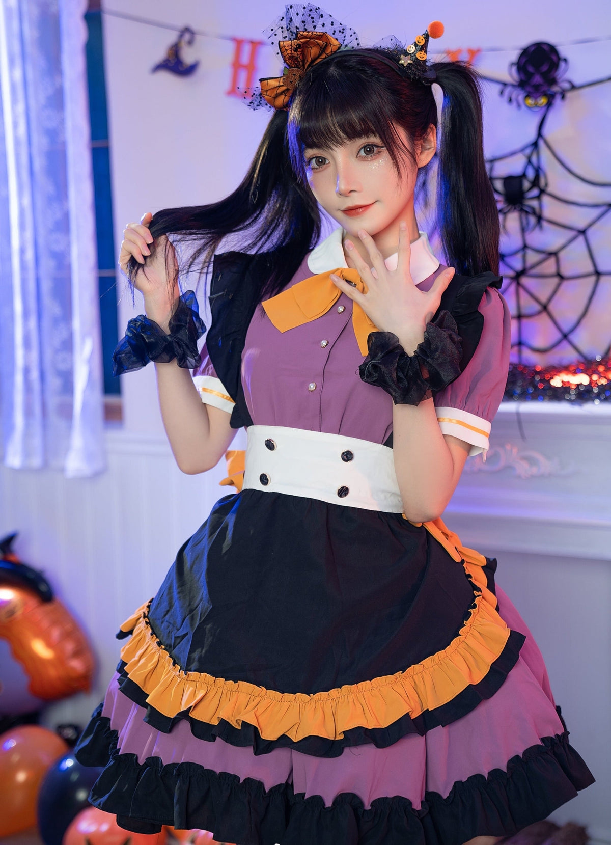 Front view of the Pumpkin Queen dress with short puff sleeves, a white buttoned waistband and orange-edged black apron panel, styled in a Halloween room.