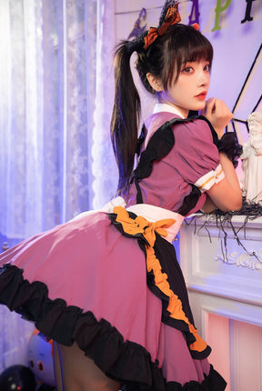 Rear three-quarter view of the Pumpkin Queen dress, showing the broad white back bow above the purple skirt and black ruffled hem.