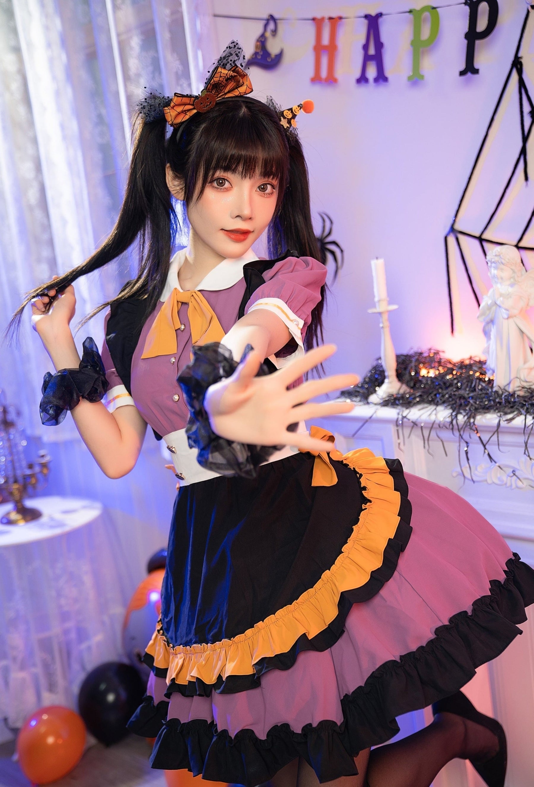 Purple Halloween dress photographed as the model reaches toward the camera, with the orange neck bow, black apron panel and layered skirt in view.