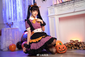 Side view of the Pumpkin Queen dress on a seated model near Halloween balloons, with the tiered skirt and orange apron trim visible.