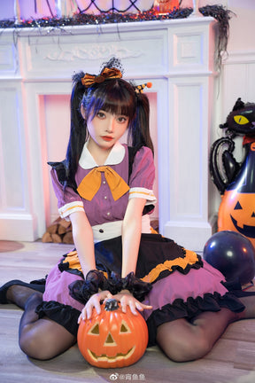 Full seated portrait of the purple ruffle dress in front of a decorated fireplace, with a pumpkin bucket centered beneath the white waistband.