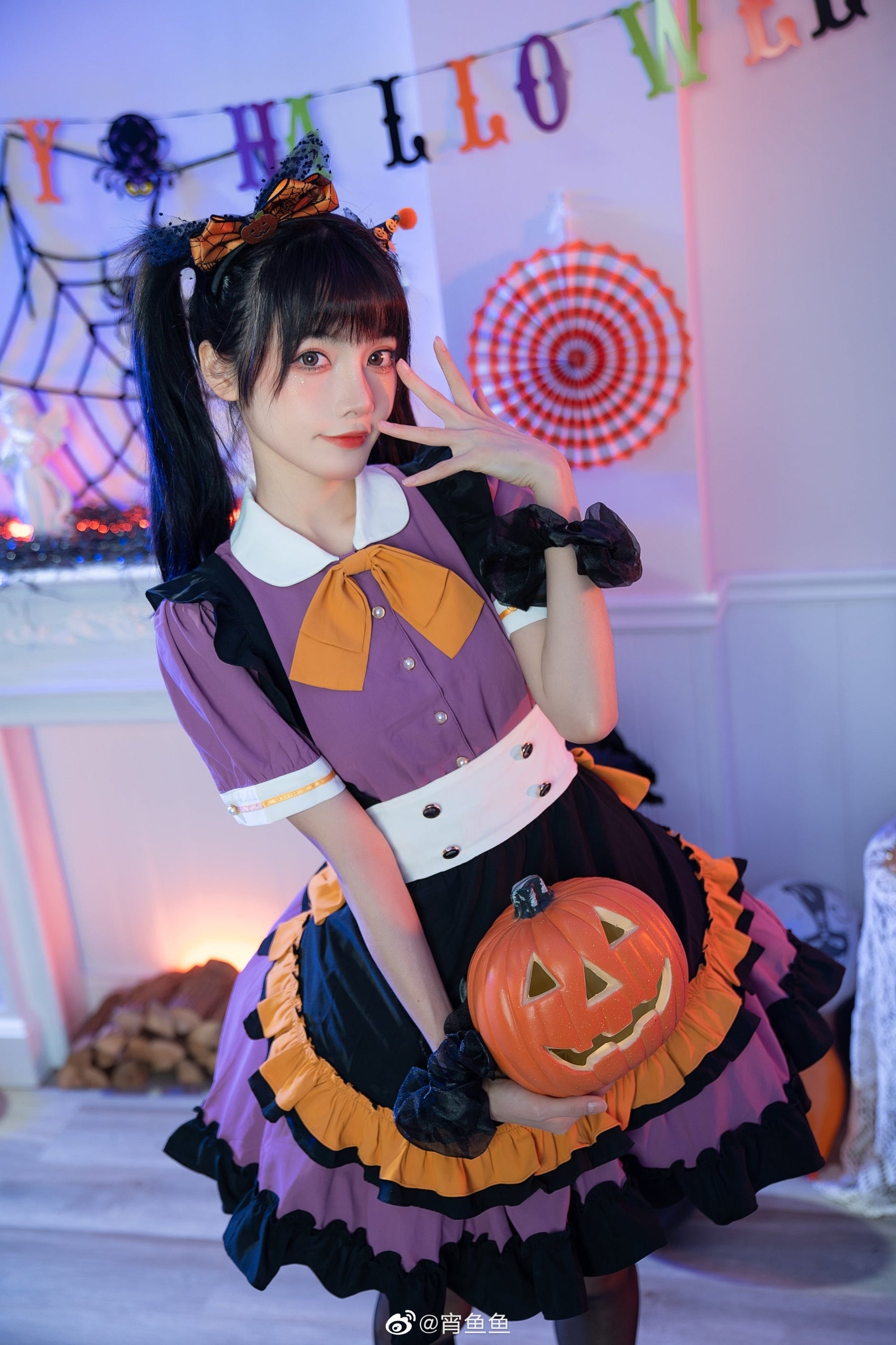 Angled portrait of the purple Halloween dress with a pumpkin bucket at the waist and the model's hand near the face, framed by Halloween decorations.