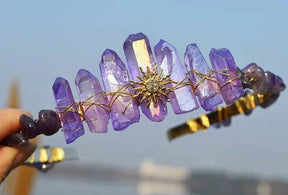 Purple crystal tiara with a gold-tone sunburst emblem, showing tall violet points above the decorative centre.