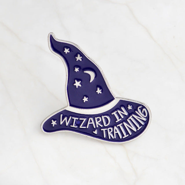 Purple Wizard in Training enamel pin with silver-tone lettering, a crescent moon and scattered stars.