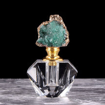 Closer view of the green crystal-topped bottle, showing its faceted clear base and slim dauber inside the neck.