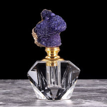 Purple quartz-topped perfume bottle with a gold-tone neck, shown upright against a black background.