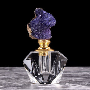 Purple quartz-topped perfume bottle with a gold-tone neck, shown upright against a black background.