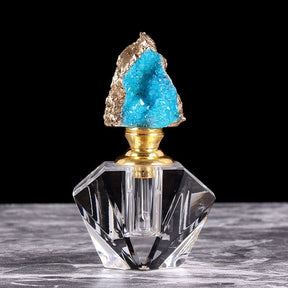 Bright blue crystal-topped perfume bottle, with an irregular cluster stopper above a gold-tone neck and angular clear base.