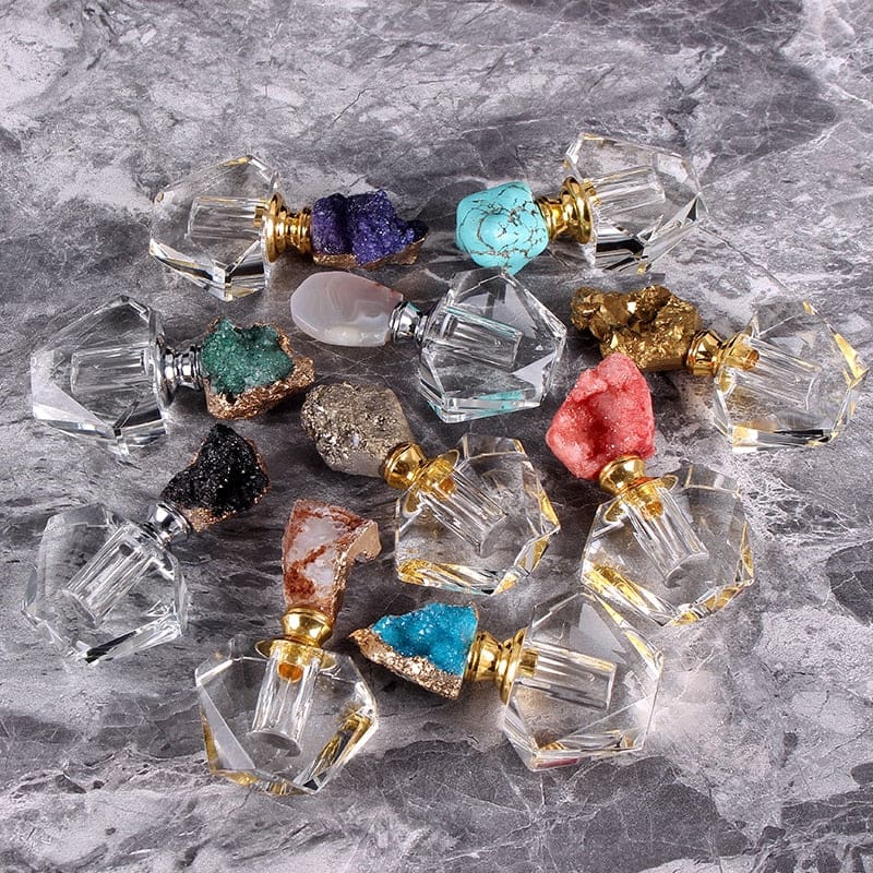 Assorted crystal-topped perfume bottles arranged on a gray marble-pattern surface, including additional display colours beyond the listed options.
