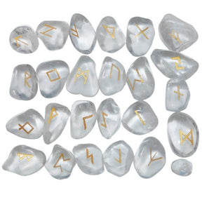Quartz rune stone set laid out in rows, showing individual gold-coloured characters and one unmarked stone against clear and milky white surfaces.