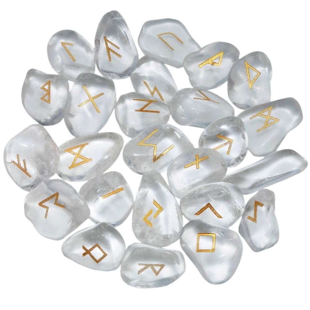 A loose pile of quartz rune stones with clear and milky white surfaces, rounded edges and gold-coloured rune marks visible across the top.