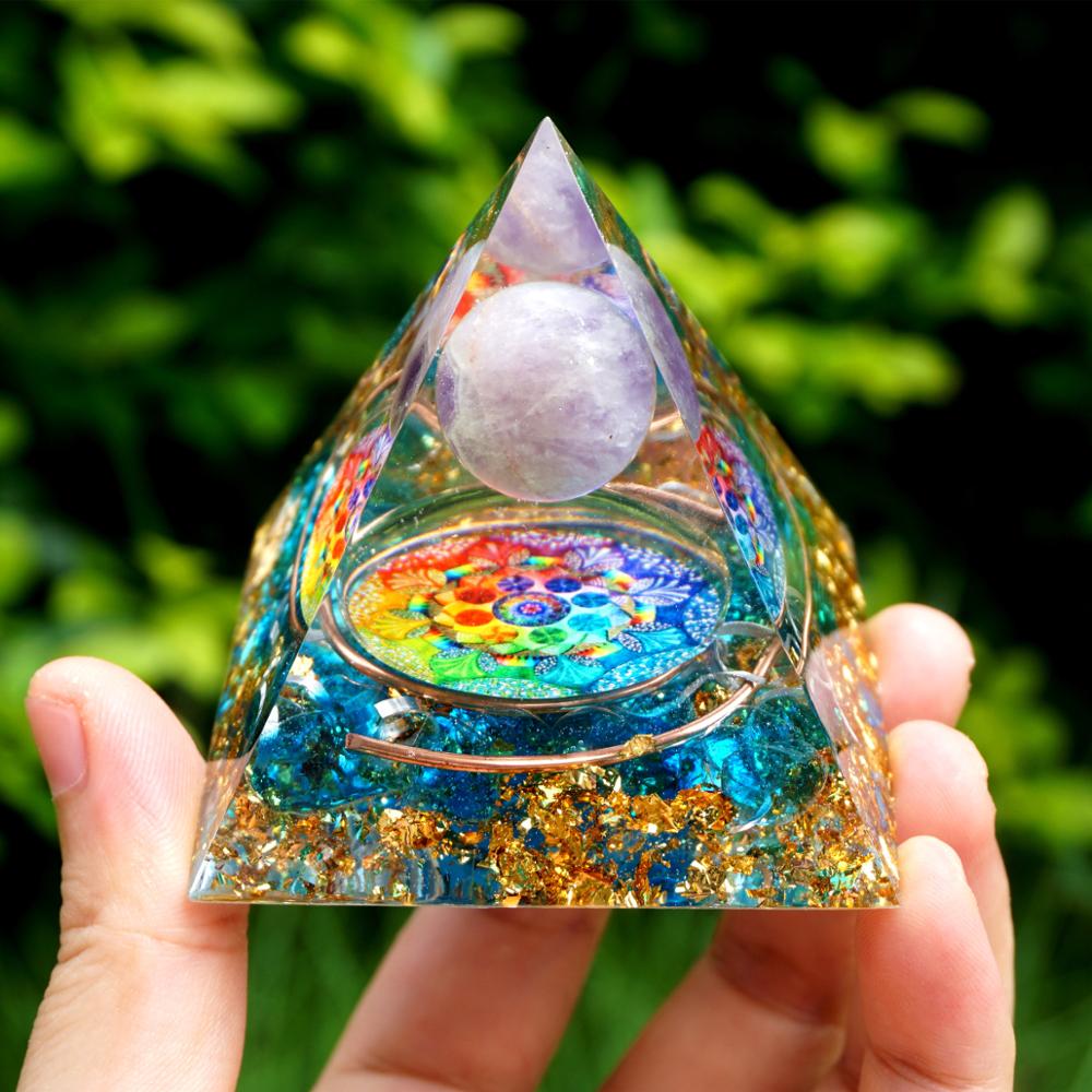 Rainbow mandala orgone pyramid with a pale purple sphere, blue stone details and gold-tone flecks. Front view held outdoors with a copper ring around the rainbow centre.