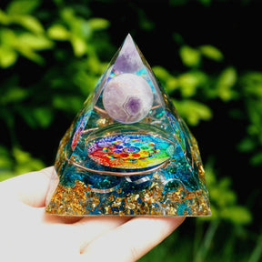 Additional view of Rainbow mandala orgone pyramid with a pale purple sphere, blue stone details and gold-tone flecks. The repeated palm view shows the amethyst sphere and multicoloured inlay.